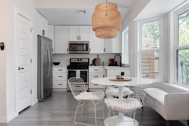 4601 Candletree Ln, Austin, TX 78744 - kitchen with appliances with stainless steel finishes, a sink, white cabinetry, and light wood-type flooring