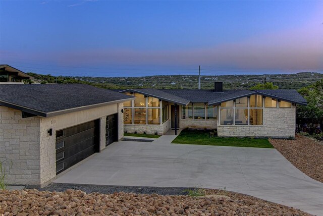 19543 Lakehurst Loop, Spicewood, TX 78669 - view of front of house with stone siding, a sunroom, and a garage