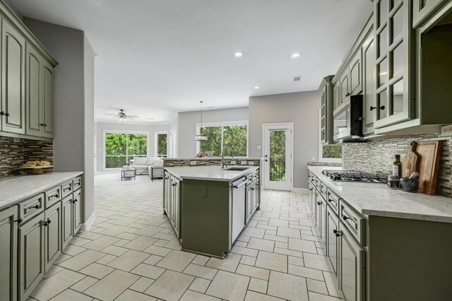 12004 Mira Mesa Dr, Austin, TX 78732 - kitchen featuring a sink, tasteful backsplash, stainless steel appliances, a center island with sink, and baseboards