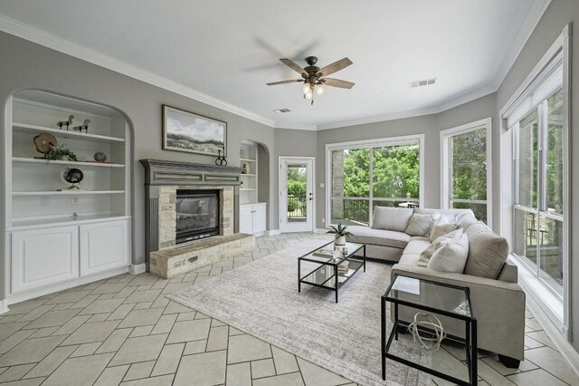 12004 Mira Mesa Dr, Austin, TX 78732 - living area featuring arched walkways, a glass covered fireplace, a ceiling fan, ornamental molding, and built in features