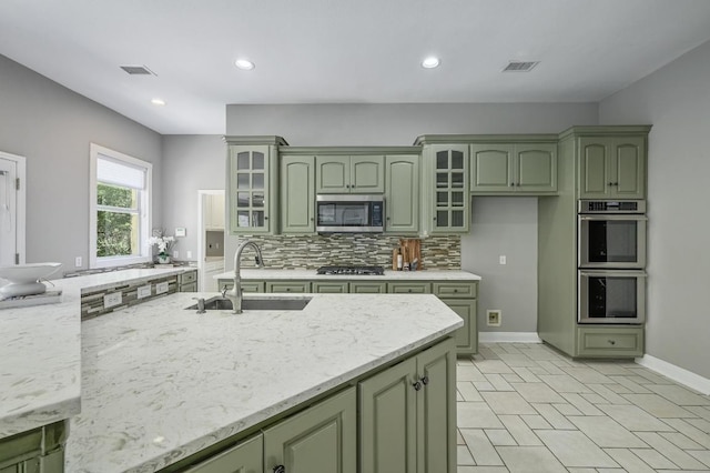 12004 Mira Mesa Dr, Austin, TX 78732 - kitchen with green cabinetry, stainless steel appliances, tasteful backsplash, recessed lighting, and glass insert cabinets