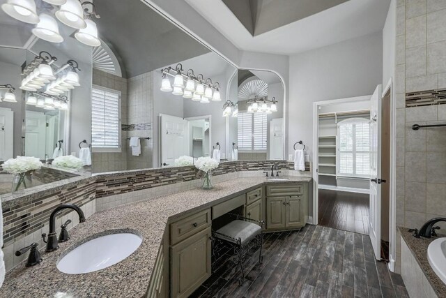 12004 Mira Mesa Dr, Austin, TX 78732 - bathroom featuring a chandelier, a walk in closet, double vanity, tiled bath, and wood finished floors