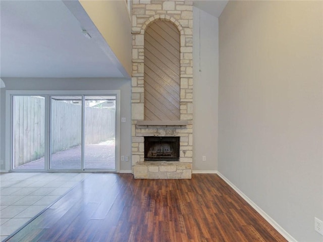 1710 Cinnamon Path, Austin, TX 78704 - unfurnished living room with wood finished floors, a stone fireplace, baseboards, and vaulted ceiling