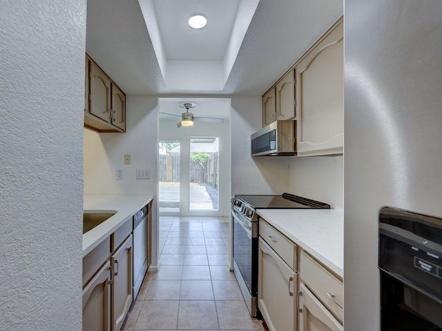 1710 Cinnamon Path, Austin, TX 78704 - kitchen with appliances with stainless steel finishes, light countertops, a ceiling fan, a raised ceiling, and light tile patterned flooring