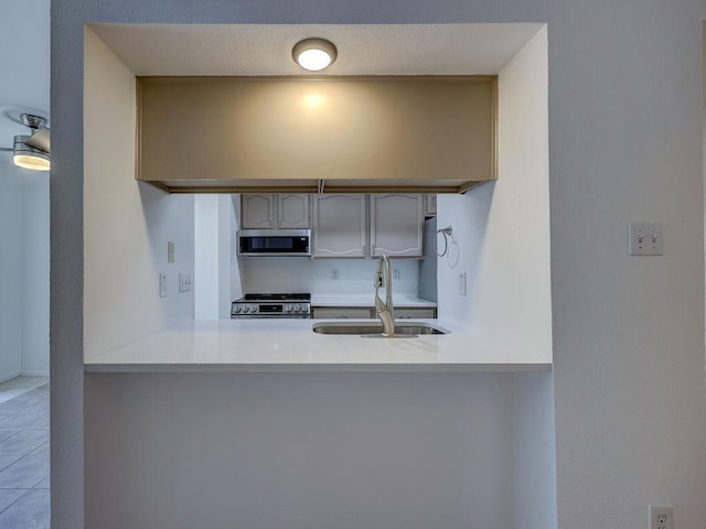1710 Cinnamon Path, Austin, TX 78704 - kitchen featuring appliances with stainless steel finishes, a sink, tile patterned floors, a peninsula, and light countertops