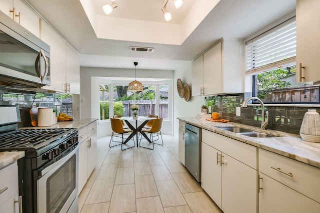 10300 Parkfield Dr, Austin, TX 78758 - kitchen with stainless steel appliances, a tray ceiling, backsplash, and light stone counters