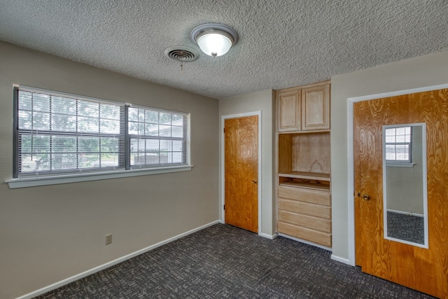 111 Dove Rd, Highland Haven, TX 78654 - unfurnished bedroom featuring dark carpet, baseboards, and a textured ceiling