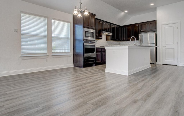 20908 Akbash Ln, Pflugerville, TX 78660 - kitchen featuring stainless steel appliances, light countertops, under cabinet range hood, a chandelier, and light wood finished floors