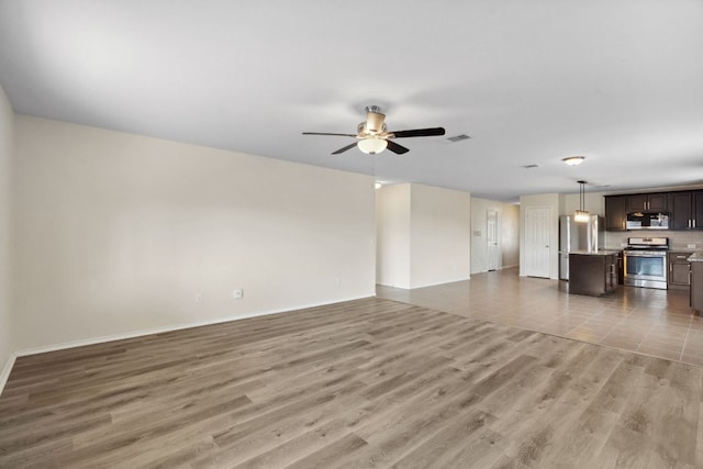 4608 Cleto St, Austin, TX 78725 - unfurnished living room with a ceiling fan, light wood-style floors, and baseboards