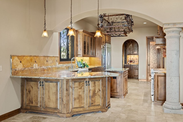 507 Sandy Mountain Dr, Sunrise Beach, TX 78643 - kitchen featuring arched walkways, light stone counters, a sink, a peninsula, and tasteful backsplash