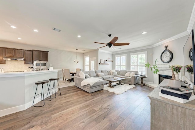 2407 Powderham Ln S, Cedar Park, TX 78613 - living area featuring light wood-style flooring, ornamental molding, recessed lighting, ceiling fan, and a fireplace
