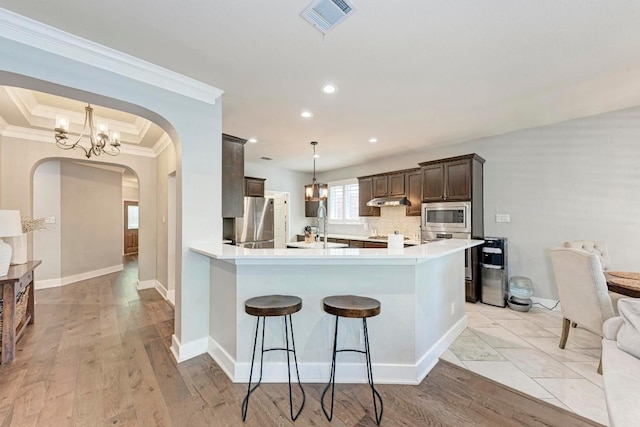 2407 Powderham Ln S, Cedar Park, TX 78613 - kitchen with appliances with stainless steel finishes, arched walkways, crown molding, dark brown cabinetry, and light countertops