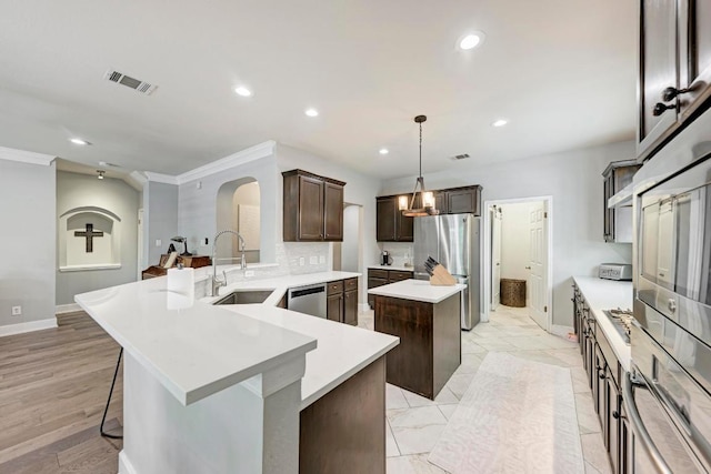 2407 Powderham Ln S, Cedar Park, TX 78613 - kitchen with a sink, a kitchen island, appliances with stainless steel finishes, dark brown cabinetry, and baseboards