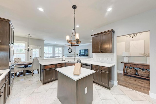2407 Powderham Ln S, Cedar Park, TX 78613 - kitchen with dark brown cabinets, a chandelier, a peninsula, light countertops, and a sink