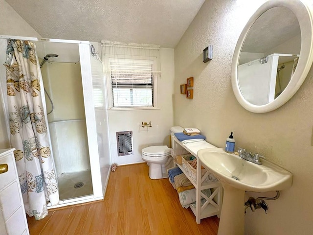 315 Skyline Dr, Sunrise Beach, TX 78643 - full bathroom with a stall shower, toilet, wood finished floors, heating unit, and a textured ceiling