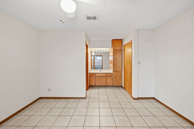 2309 Westoak Dr, Austin, TX 78704 - spare room featuring baseboards, a textured ceiling, a ceiling fan, a sink, and light tile patterned flooring