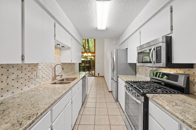 2309 Westoak Dr, Austin, TX 78704 - kitchen featuring stainless steel appliances, a sink, a textured ceiling, backsplash, and white cabinets