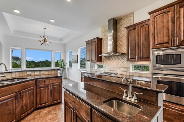 9501 Derecho Bnd, Austin, TX 78737 - kitchen with wall chimney range hood, stainless steel appliances, a sink, a tray ceiling, and recessed lighting