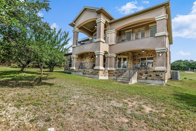 9501 Derecho Bnd, Austin, TX 78737 - rear view of house featuring a balcony, stucco siding, stone siding, and a lawn