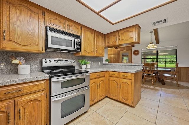 300 W Sequoia Spur, Georgetown, TX 78628 - kitchen with appliances with stainless steel finishes, brown cabinets, light countertops, decorative backsplash, and light tile patterned flooring