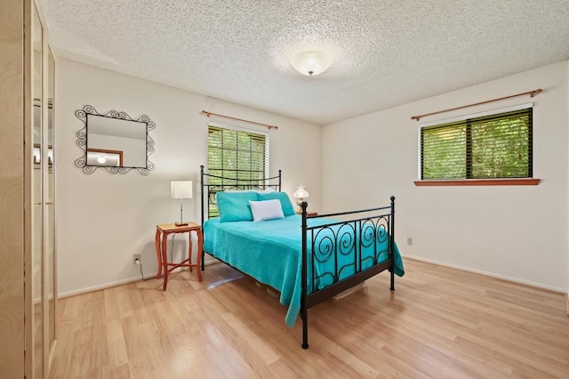 300 W Sequoia Spur, Georgetown, TX 78628 - bedroom with light wood finished floors, a textured ceiling, and baseboards