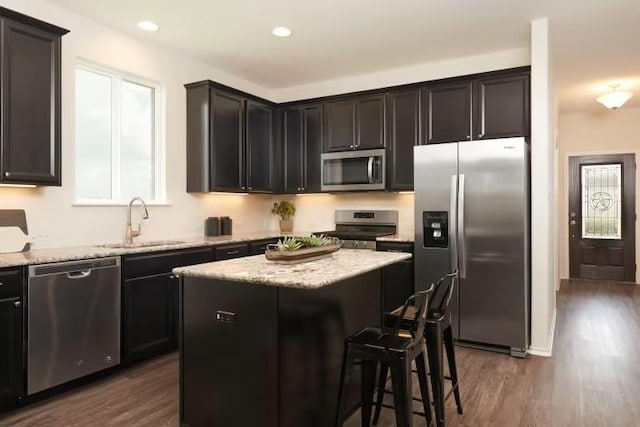 814 Cherrystone Loop, Buda, TX 78610 - kitchen featuring appliances with stainless steel finishes, a sink, dark wood finished floors, a center island, and light stone counters