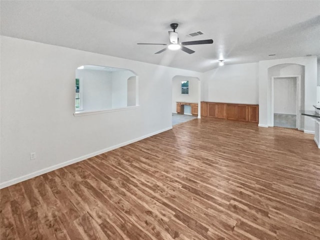 126 Waterlily Way, Hutto, TX 78634 - unfurnished living room featuring wood finished floors, ceiling fan, arched walkways, and wainscoting