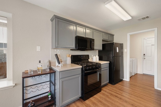 1528 Morning Mist Ln, Pflugerville, TX 78660 - kitchen with black appliances, separate washer and dryer, gray cabinets, light wood-style flooring, and light countertops