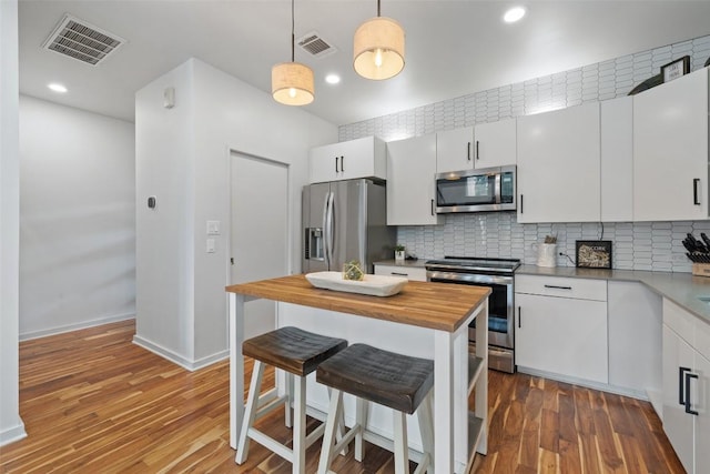 2001 Whitebead Trl, Austin, TX 78734 - kitchen featuring stainless steel appliances, butcher block counters, a breakfast bar area, backsplash, and white cabinetry