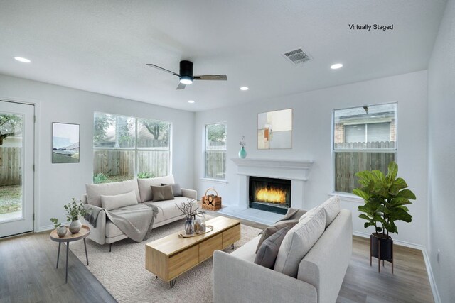 2106 Lobelia Dr, Cedar Park, TX 78613 - living area with wood finished floors, a warm lit fireplace, ceiling fan, recessed lighting, and baseboards