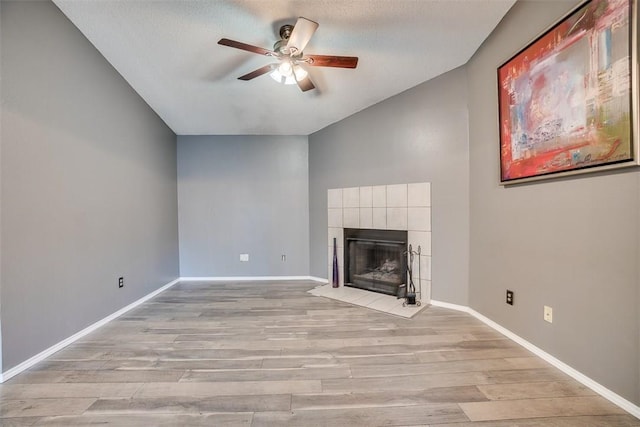 6009 Baton Rouge Dr, Austin, TX 78727 - unfurnished living room with a ceiling fan, lofted ceiling, light wood finished floors, a tile fireplace, and baseboards