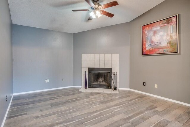 6009 Baton Rouge Dr, Austin, TX 78727 - unfurnished living room featuring a ceiling fan, light wood-style floors, a fireplace, baseboards, and a textured ceiling