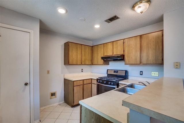 6009 Baton Rouge Dr, Austin, TX 78727 - kitchen with gas stove, under cabinet range hood, a sink, light countertops, and a peninsula