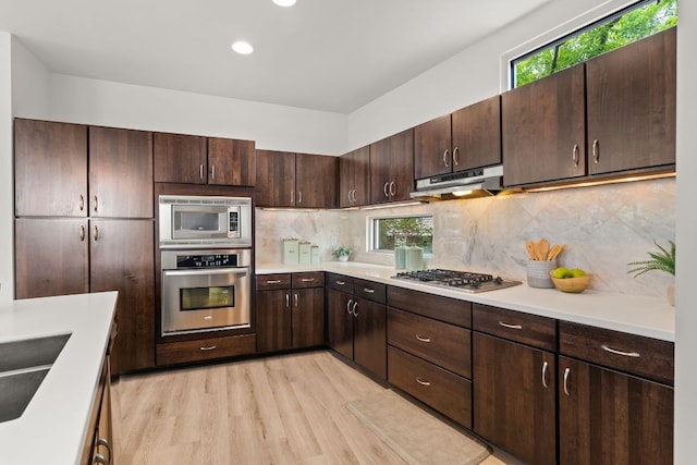 1500 Summit St Unit 4, Austin, TX 78741 - kitchen featuring stainless steel appliances, ventilation hood, light wood-style floors, light countertops, and dark brown cabinetry