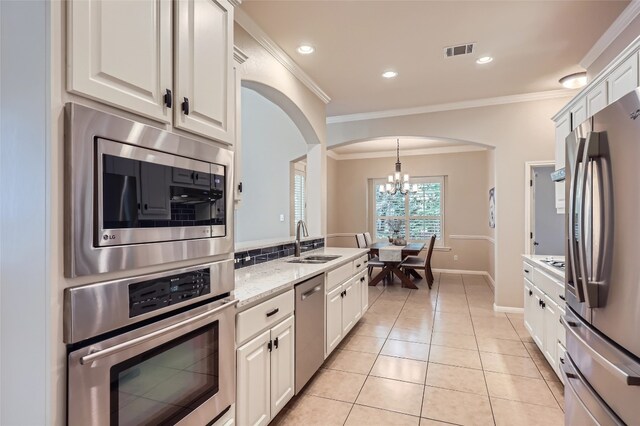 2503 Kinclaven Ct, Cedar Park, TX 78613 - kitchen with appliances with stainless steel finishes, arched walkways, a sink, a chandelier, and ornamental molding