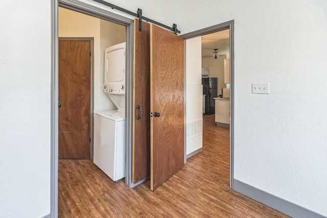 421 W San Antonio St Unit H1, San Marcos, TX 78666 - laundry area with stacked washing machine and dryer, wood finished floors, and a barn door
