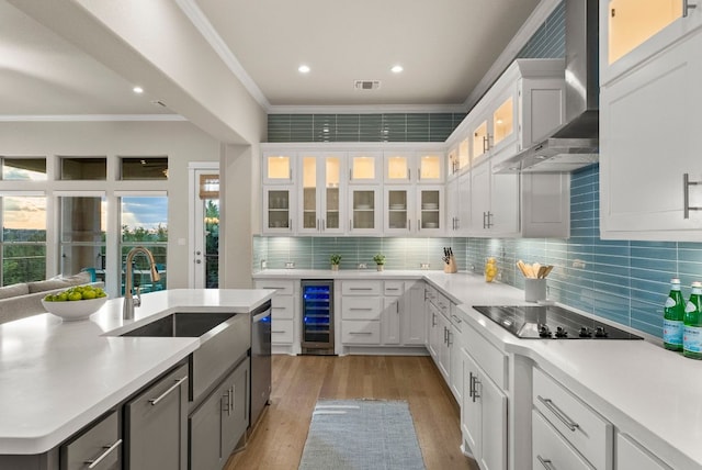 5502 Patagonia Pass, Austin, TX 78738 - kitchen with wine cooler, wall chimney exhaust hood, ornamental molding, light wood-style floors, and black electric cooktop