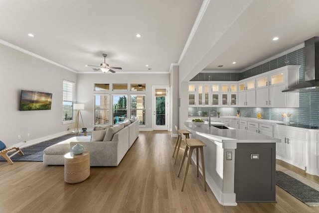 5502 Patagonia Pass, Austin, TX 78738 - kitchen featuring wall chimney range hood, crown molding, light wood-style flooring, black electric cooktop, and baseboards