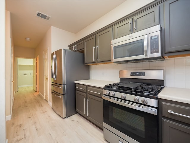 1010 Barclay Dr, Leander, TX 78641 - kitchen with appliances with stainless steel finishes, light wood-style floors, decorative backsplash, and light countertops