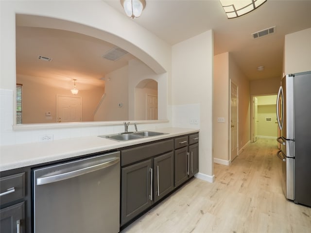 1010 Barclay Dr, Leander, TX 78641 - kitchen featuring stainless steel appliances, a sink, light wood-type flooring, light countertops, and arched walkways