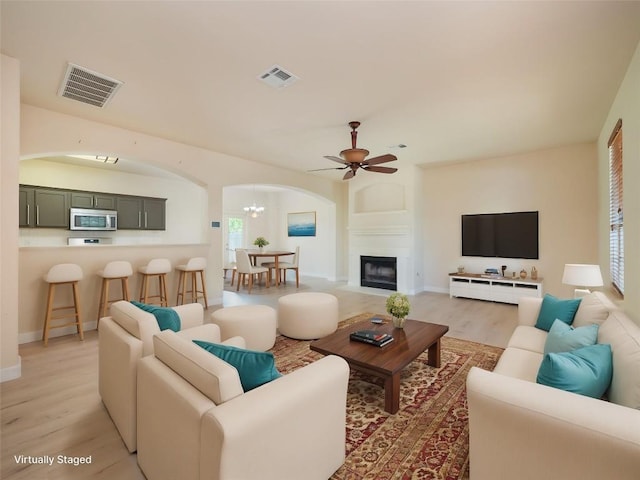 1010 Barclay Dr, Leander, TX 78641 - living area with arched walkways, light wood-type flooring, a ceiling fan, and a fireplace with flush hearth