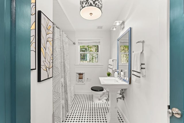 2004 Bremen St, Austin, TX 78703 - bathroom with a sink, curtained shower, baseboards, and heating unit
