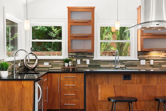 2004 Bremen St, Austin, TX 78703 - kitchen with wall chimney range hood, a sink, tasteful backsplash, brown cabinetry, and plenty of natural light