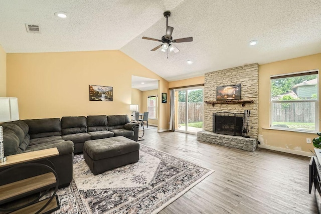 7900 Keneshaw Dr, Austin, TX 78745 - living area with a ceiling fan, a textured ceiling, lofted ceiling, wood finished floors, and a stone fireplace