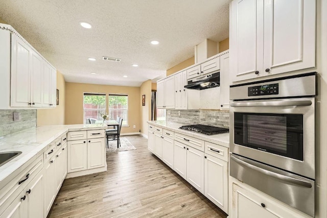 7900 Keneshaw Dr, Austin, TX 78745 - kitchen featuring stainless steel appliances, a warming drawer, recessed lighting, a peninsula, and light wood finished floors