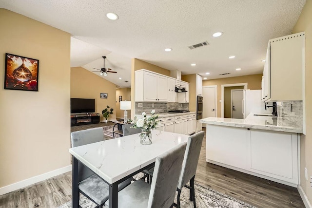 7900 Keneshaw Dr, Austin, TX 78745 - kitchen featuring wood finished floors, backsplash, ceiling fan, white cabinetry, and recessed lighting