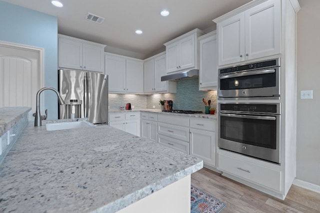 2809 Coral Valley Dr, Leander, TX 78641 - kitchen with appliances with stainless steel finishes, backsplash, under cabinet range hood, white cabinets, and recessed lighting