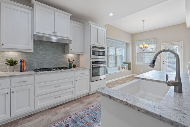 2809 Coral Valley Dr, Leander, TX 78641 - kitchen with under cabinet range hood, appliances with stainless steel finishes, a sink, backsplash, and recessed lighting