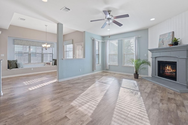 2809 Coral Valley Dr, Leander, TX 78641 - unfurnished living room featuring a glass covered fireplace, a chandelier, ceiling fan, wood finished floors, and recessed lighting