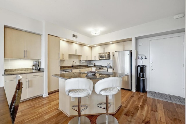54 Rainey St Unit 814, Austin, TX 78701 - kitchen with stainless steel appliances, a sink, decorative backsplash, and light wood-type flooring